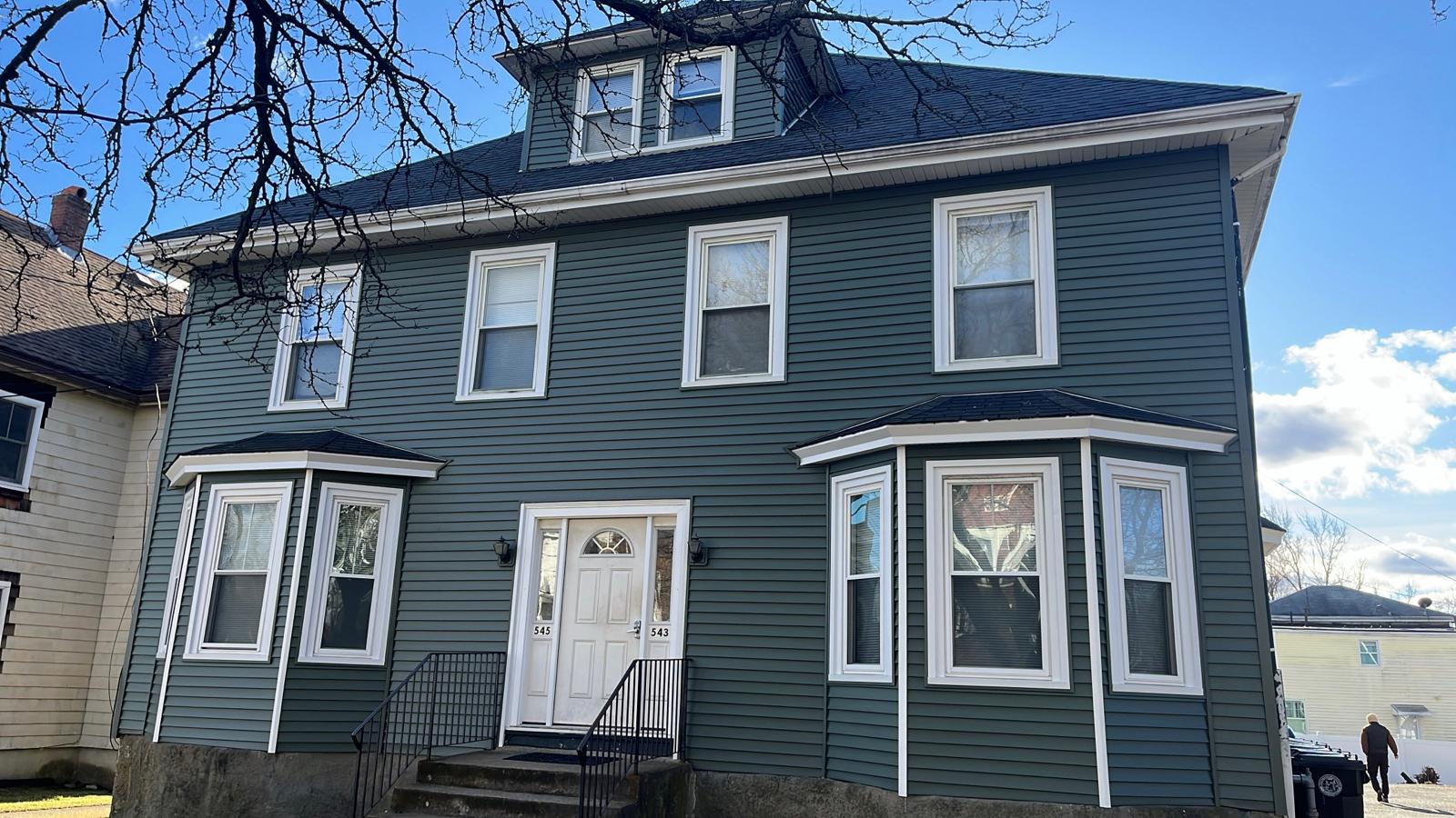 After: house with new slate green siding and white bay window trim