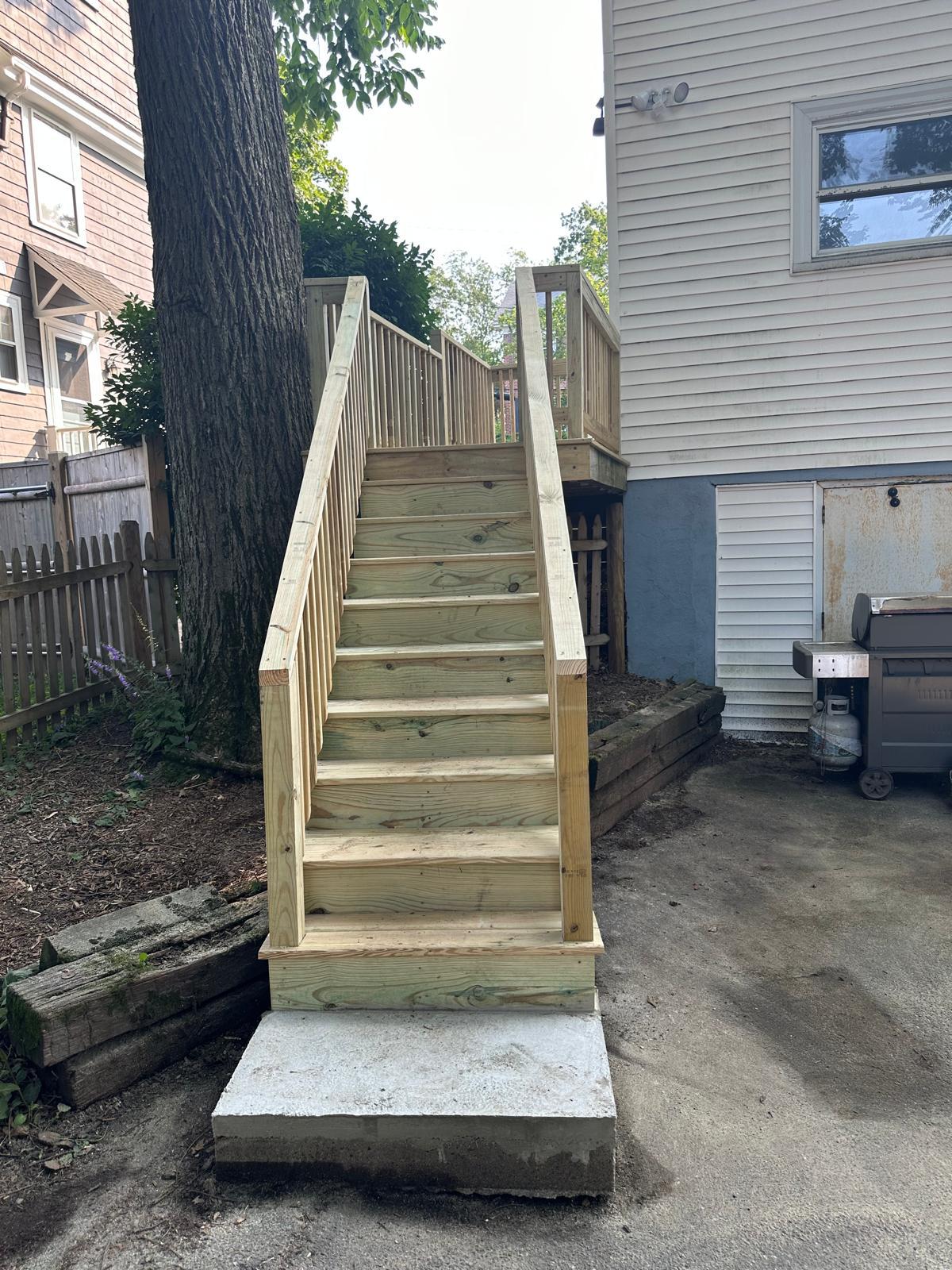 After: rebuilt pressure-treated deck stairs on a new concrete landing