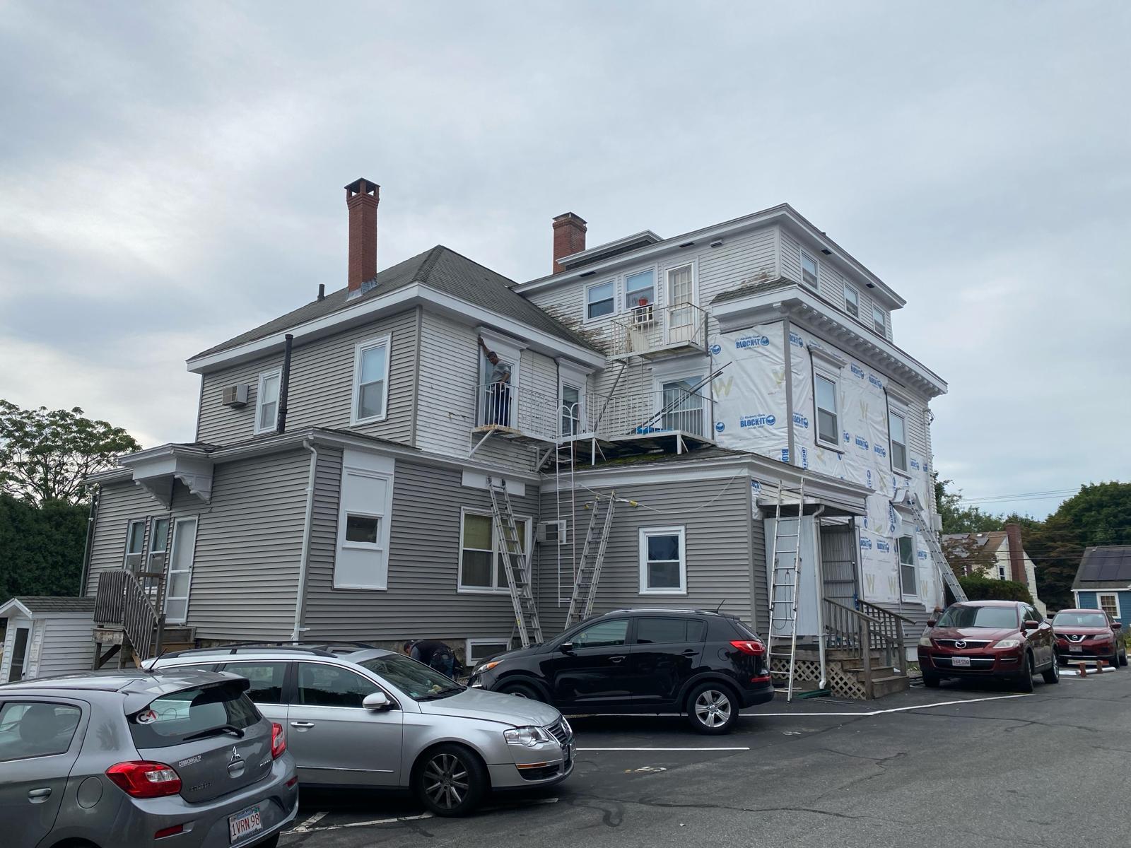 Everlast crew re-siding a multi-family house, ladders and house wrap on the walls